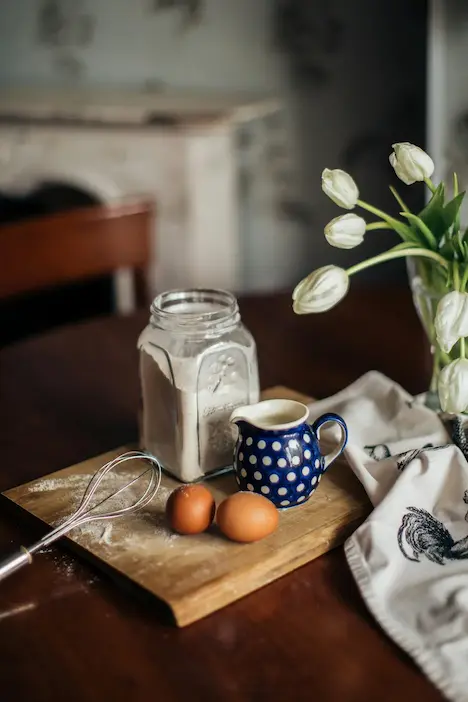 Two eggs, milk and a jar of flour